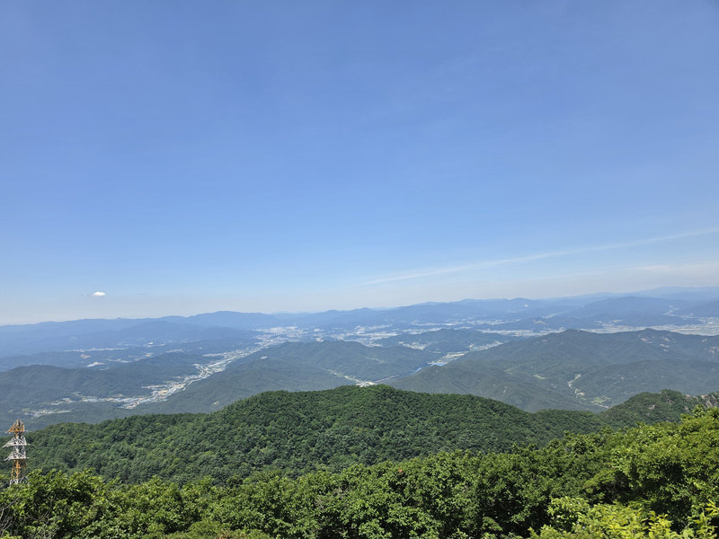 겹겹이 이어진 산줄기와 그 사이의 시가지, 넓은 파란 하늘